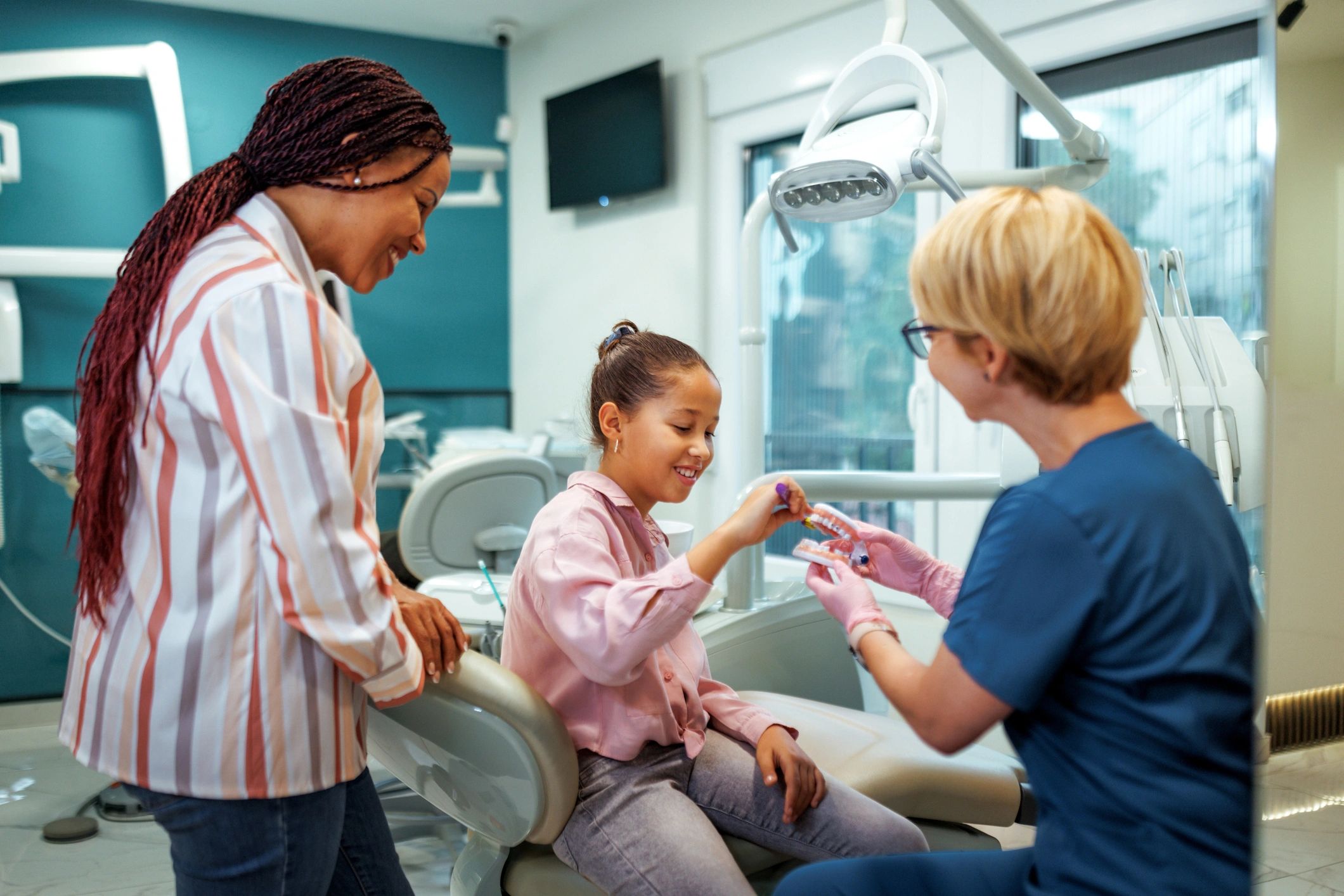 Pediatric dentist teaching a child proper brushing using a dental model